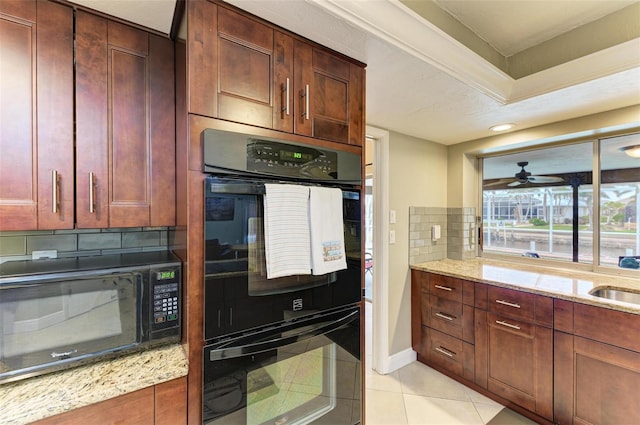 kitchen featuring sink, light tile patterned floors, backsplash, light stone countertops, and black appliances