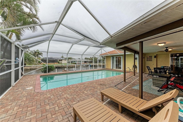 view of swimming pool featuring a patio, a water view, and a lanai