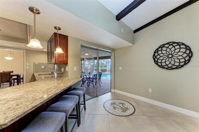 kitchen with sink, light tile patterned floors, decorative backsplash, decorative light fixtures, and kitchen peninsula