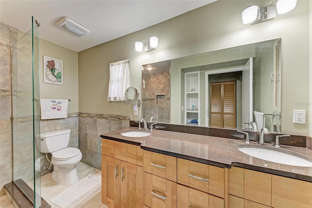 bathroom with a tile shower, tile walls, tile patterned flooring, vanity, and toilet