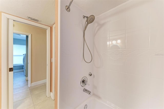 bathroom with tiled shower / bath combo, tile patterned flooring, and a textured ceiling