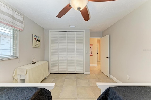 bedroom with light tile patterned floors, a closet, and ceiling fan