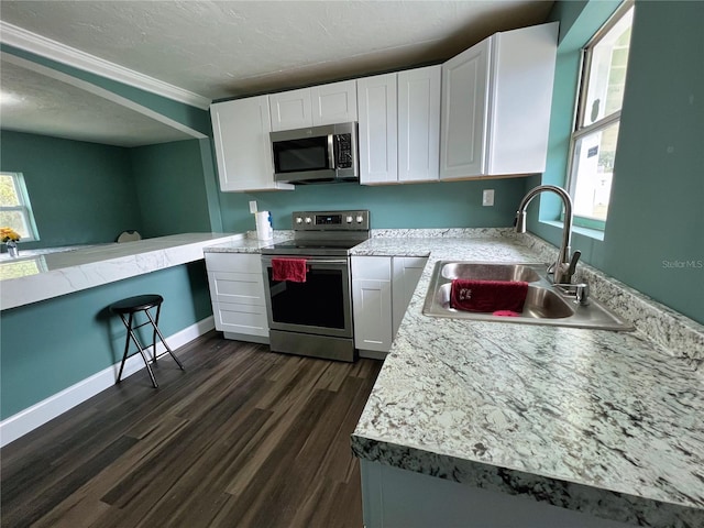 kitchen with sink, white cabinets, kitchen peninsula, stainless steel appliances, and dark wood-type flooring