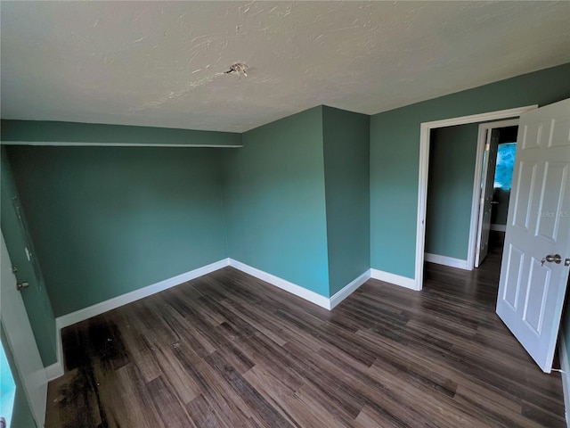 spare room with dark hardwood / wood-style floors and a textured ceiling