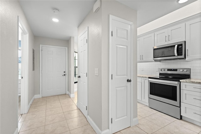 kitchen featuring stainless steel appliances, light tile patterned floors, white cabinets, and decorative backsplash