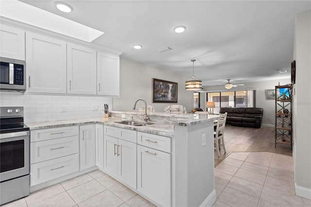 kitchen with appliances with stainless steel finishes, sink, white cabinets, light tile patterned floors, and kitchen peninsula