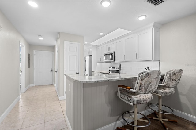 kitchen featuring white cabinetry, a breakfast bar, appliances with stainless steel finishes, and kitchen peninsula