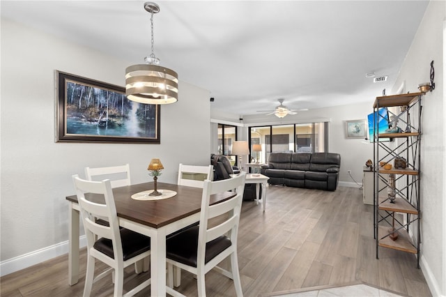 dining space with wood-type flooring and ceiling fan with notable chandelier