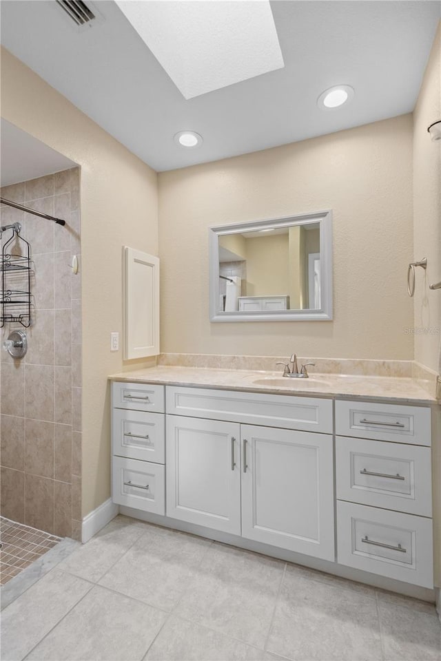 bathroom featuring vanity, tile patterned flooring, and a tile shower