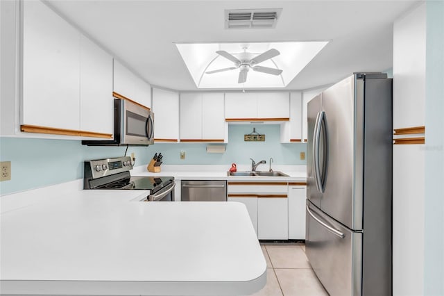 kitchen with sink, light tile patterned floors, appliances with stainless steel finishes, white cabinetry, and kitchen peninsula