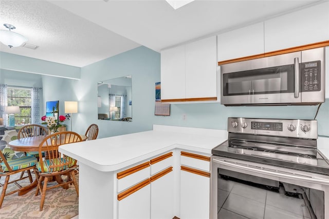 kitchen featuring stainless steel appliances, kitchen peninsula, a textured ceiling, and white cabinets