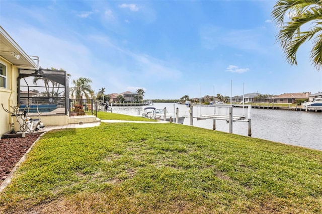 view of yard with glass enclosure, a water view, and a boat dock