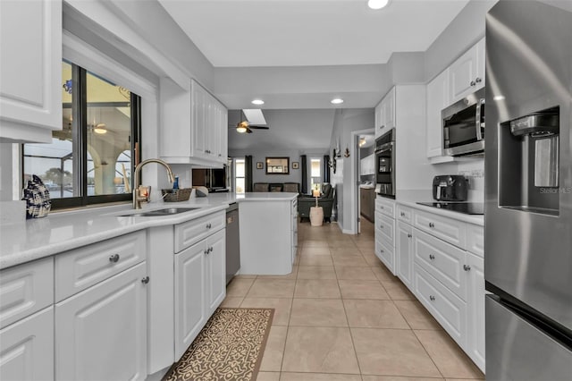 kitchen with kitchen peninsula, sink, white cabinets, light tile patterned floors, and stainless steel appliances