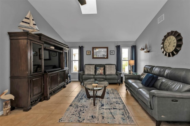 living room with vaulted ceiling with skylight and light tile patterned floors