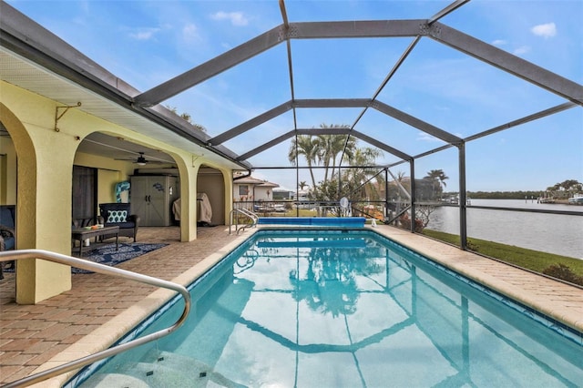 view of pool featuring ceiling fan, a lanai, a water view, and a patio area