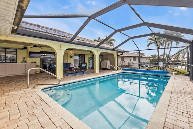 view of pool featuring glass enclosure, a patio area, an outdoor living space, and ceiling fan