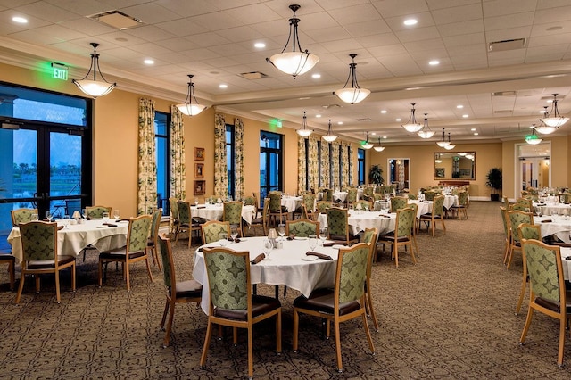 dining space with a tray ceiling, french doors, crown molding, and dark colored carpet