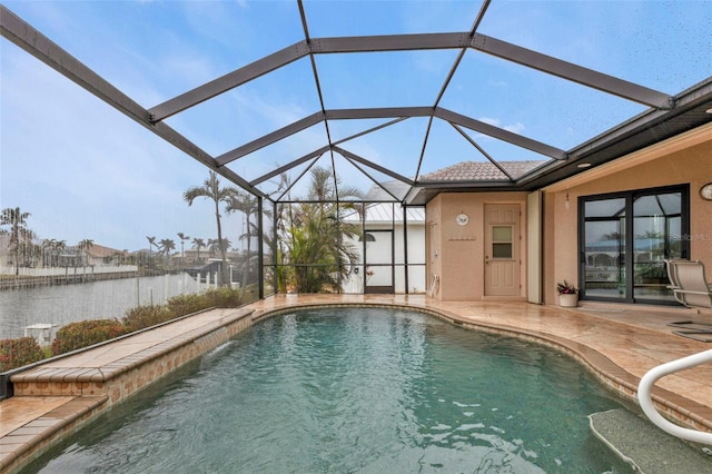 view of pool featuring a patio area, a water view, and glass enclosure