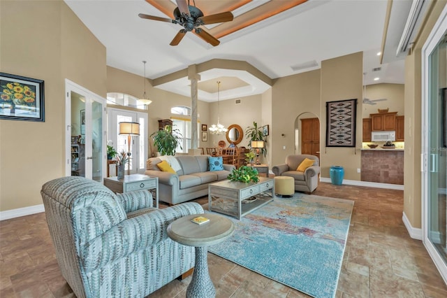 living room featuring ceiling fan with notable chandelier and a high ceiling