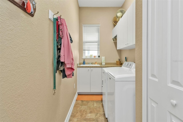 clothes washing area featuring cabinets, sink, and washer and dryer