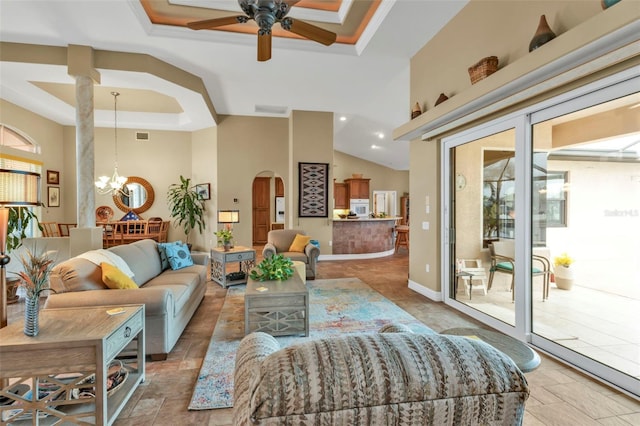 living room featuring a tray ceiling, ceiling fan with notable chandelier, and a high ceiling