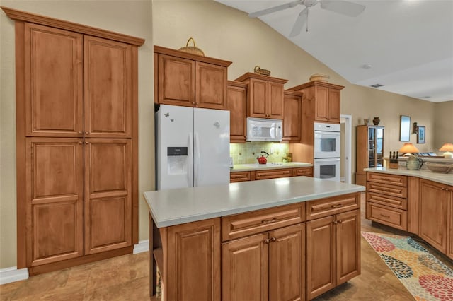 kitchen featuring white appliances, ceiling fan, a center island, tasteful backsplash, and vaulted ceiling