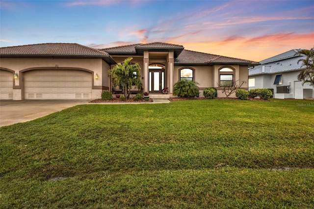 mediterranean / spanish house featuring a garage and a lawn