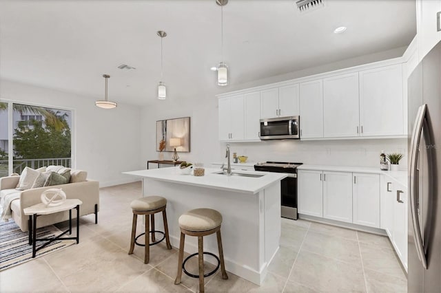 kitchen featuring pendant lighting, stainless steel appliances, a kitchen island with sink, and sink