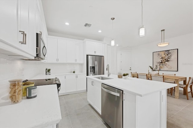 kitchen featuring white cabinetry, stainless steel appliances, a kitchen island with sink, and pendant lighting