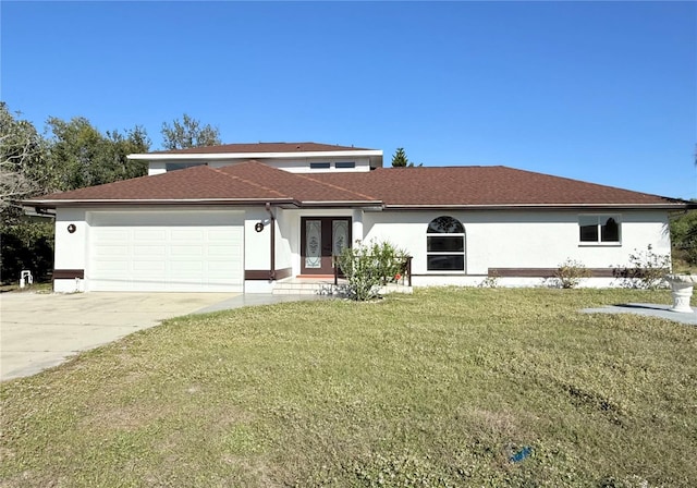 view of front of home featuring french doors, stucco siding, an attached garage, a front yard, and driveway