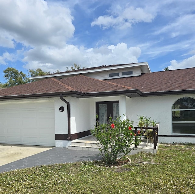 view of front of house with a garage, a shingled roof, and stucco siding