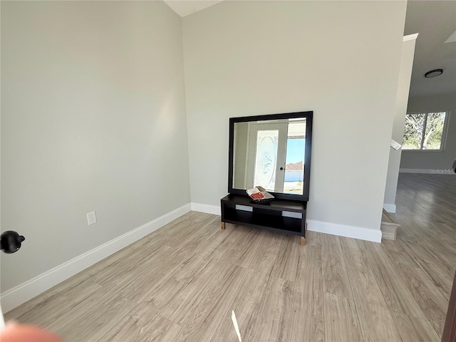 empty room featuring a high ceiling, baseboards, and wood finished floors