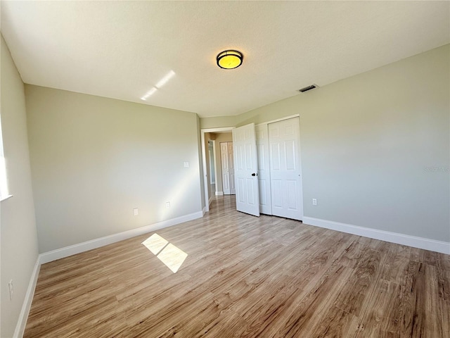 spare room with baseboards, a textured ceiling, visible vents, and light wood-style floors