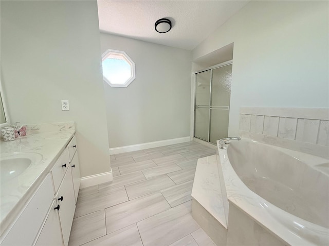 bathroom featuring a shower stall, vanity, a textured ceiling, baseboards, and a bath