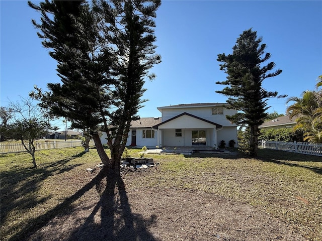 rear view of house featuring fence and a lawn