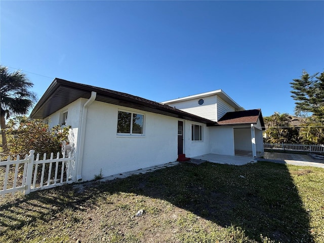 view of front of home featuring a front yard, a patio area, fence, and stucco siding