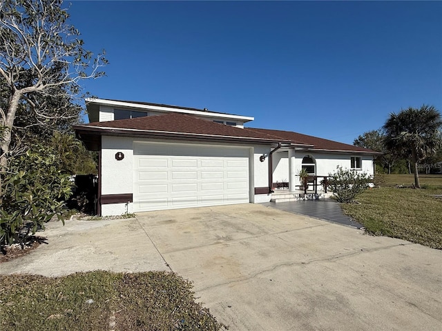 view of front of home with a garage, driveway, and stucco siding