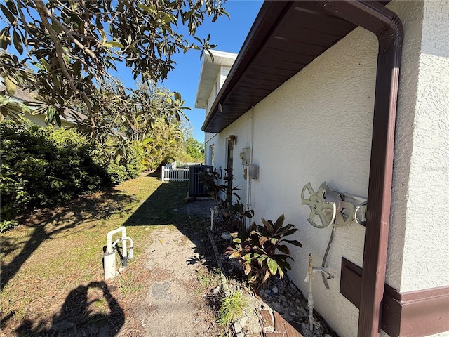 view of home's exterior featuring central air condition unit, a yard, fence, and stucco siding