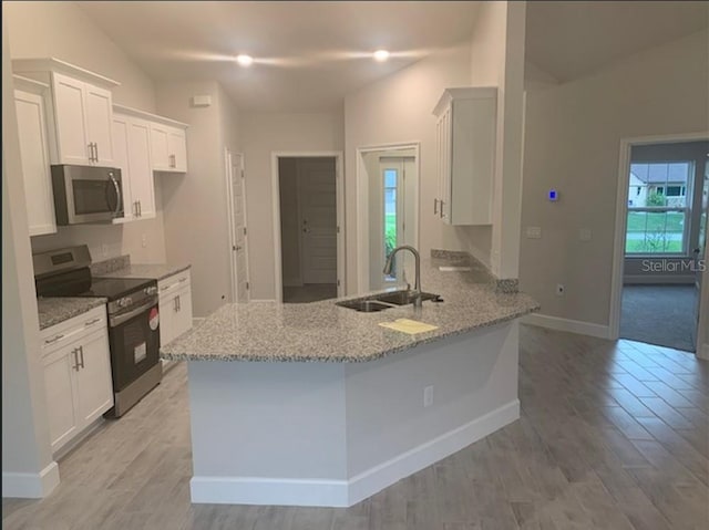 4063 Conestoga St, Port Charlotte, FL 33948 - kitchen with stainless steel appliances, light stone countertops, white cabinetry, a peninsula, and light wood-style floors