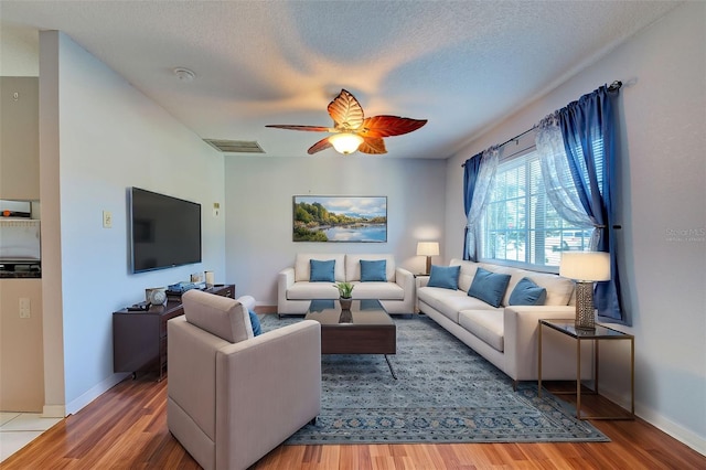 living room featuring a textured ceiling, wood-type flooring, and ceiling fan