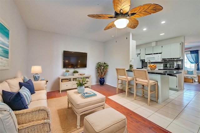 living room featuring ceiling fan, sink, and light tile patterned floors