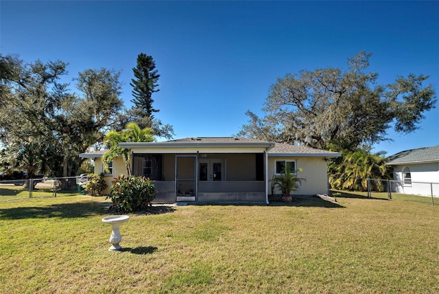 rear view of house with a sunroom and a lawn