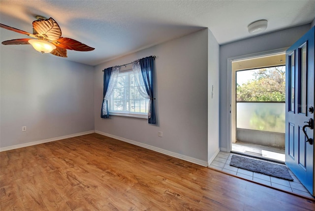 foyer entrance featuring a textured ceiling, ceiling fan, and light hardwood / wood-style flooring