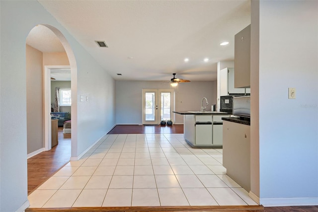 kitchen with sink, light tile patterned floors, kitchen peninsula, ceiling fan, and backsplash