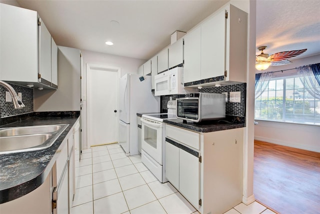 kitchen with light tile patterned flooring, sink, white cabinets, ceiling fan, and white appliances