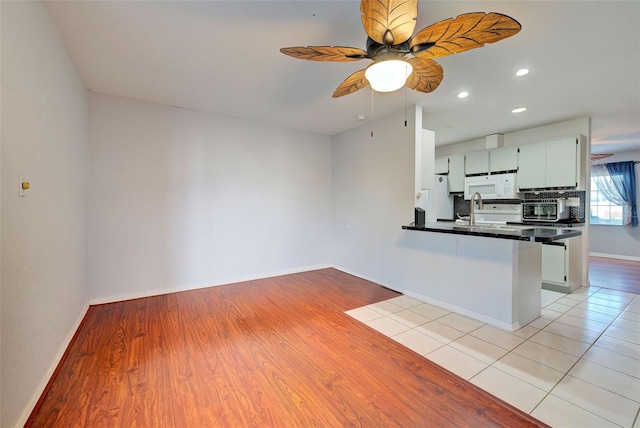 kitchen with tasteful backsplash, sink, kitchen peninsula, and white cabinets