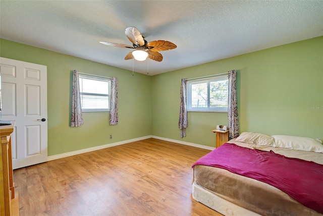 bedroom featuring multiple windows, a textured ceiling, ceiling fan, and light hardwood / wood-style floors