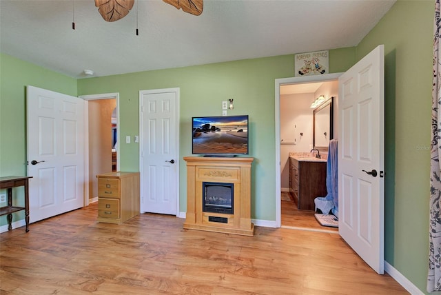 living room featuring ceiling fan, sink, and light hardwood / wood-style floors