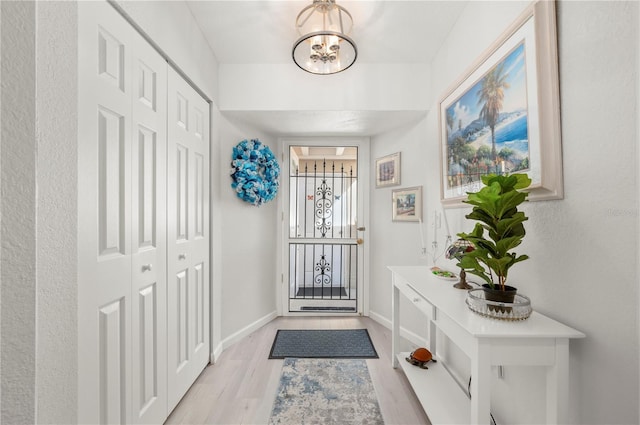 foyer entrance with light wood-type flooring and a notable chandelier