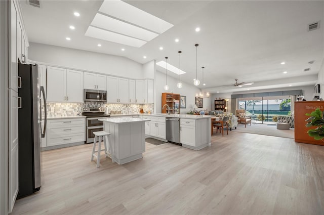 kitchen with decorative light fixtures, a center island with sink, stainless steel appliances, and a breakfast bar area